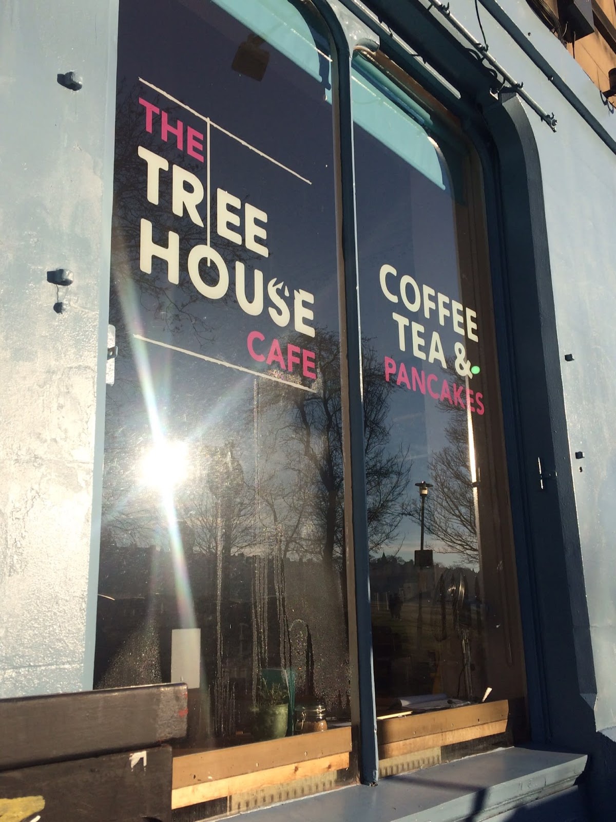 The cafe window: THE TREE HOUSE CAFE in cream and pink on navy glass, with COFFEE TEA and PANCAKES alongside.